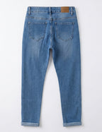 Jean 7/8ème slim bleu denim seul sur fond neutre, vue de dos - Voggo